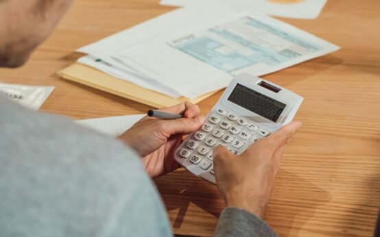 Person using a calculator at a desk with financial documents. Modern business concept.