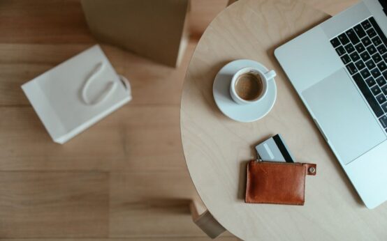 Minimalist top view of a workspace with coffee, laptop, and wallet on a wooden table.
