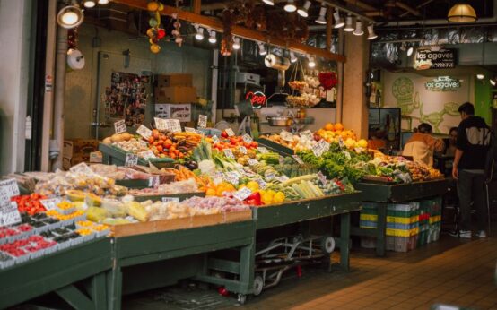 Colorful indoor market stall with an array of fresh fruits and vegetables on display.